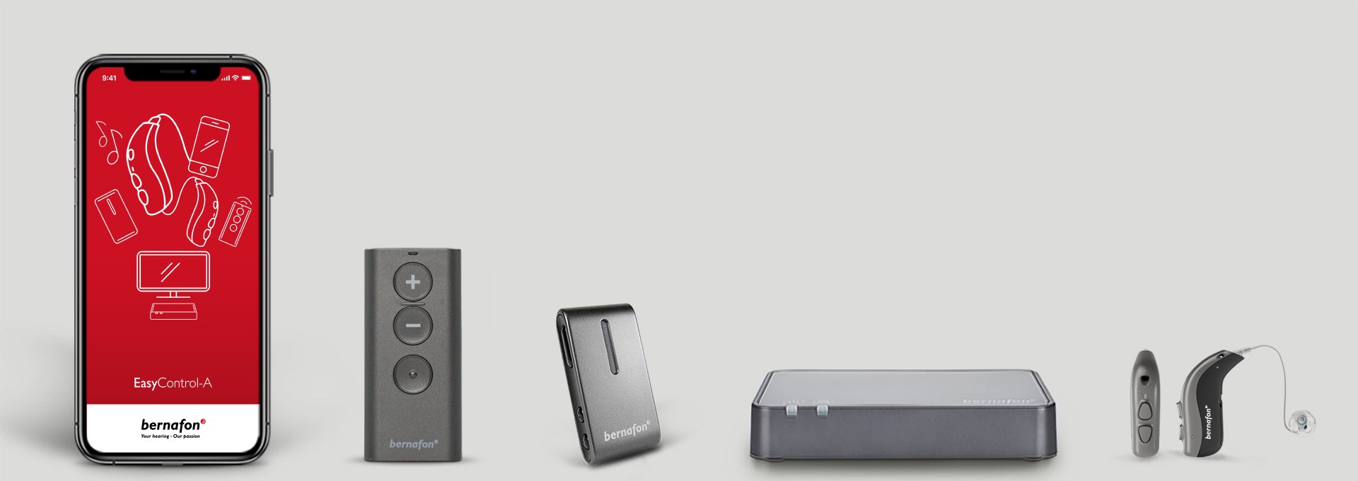 Bernafon accessories lined up, including Bernafon app on a smartphone, TV adapter, remote control, hearing aids and SoundClip-A