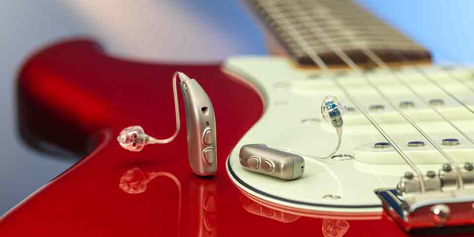 The new Bernafon Viron miniRITE T R lithium-ion rechargeable hearing aids on a red electric guitar showing reflections.