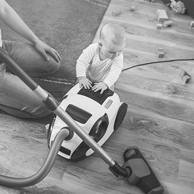 Infant standing against a vacuum cleaner